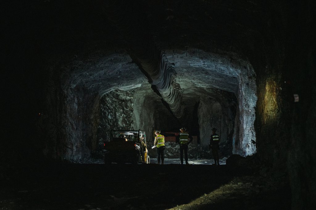 Three people standing in a dark, newly excavated cavern